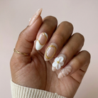 Hand with decorative nail art featuring flowers on a plain background
