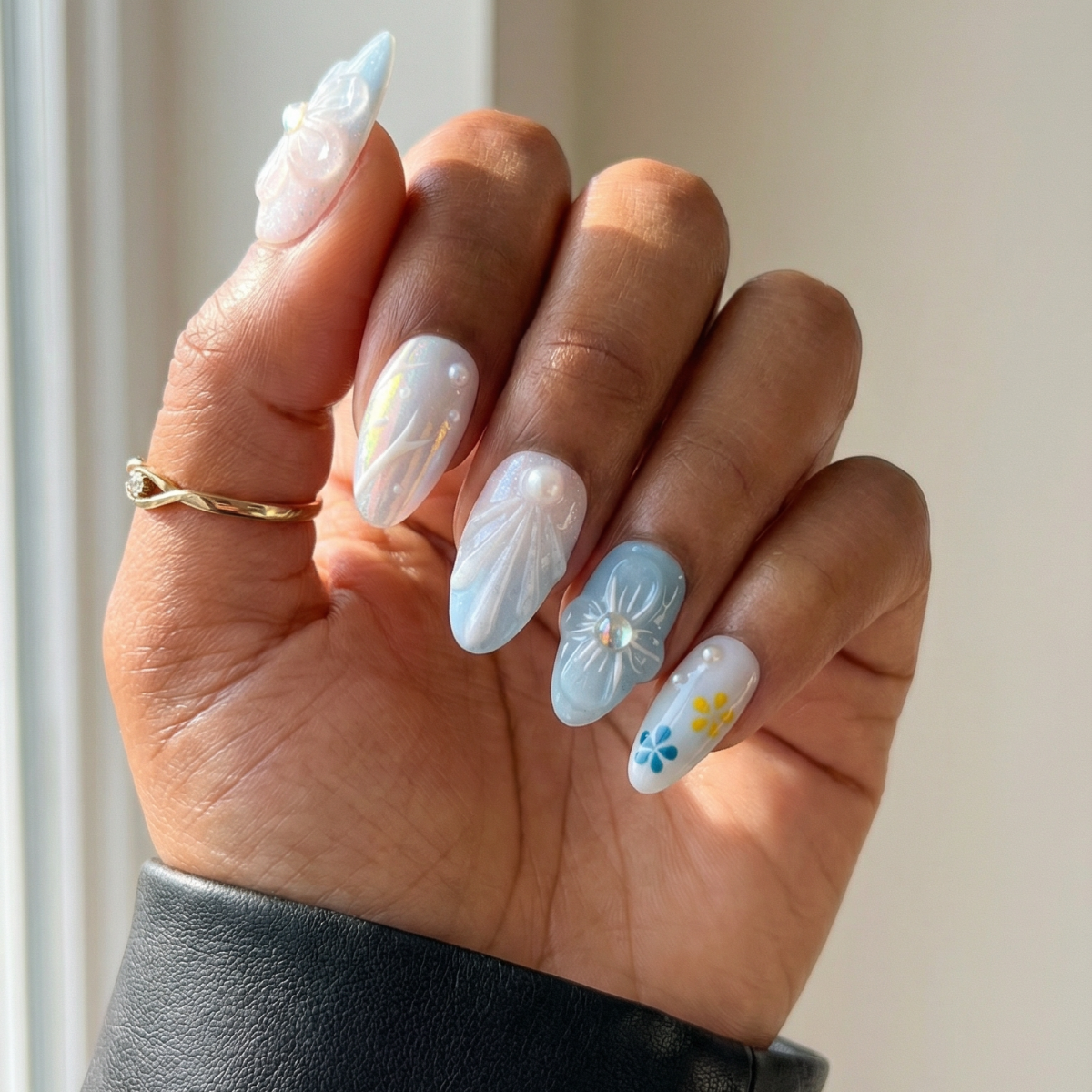 Hand with decorative nail art holding a black sleeve against a neutral background