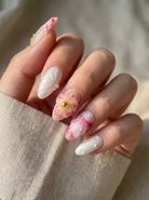 Hand with pink and white floral nail art on a neutral background